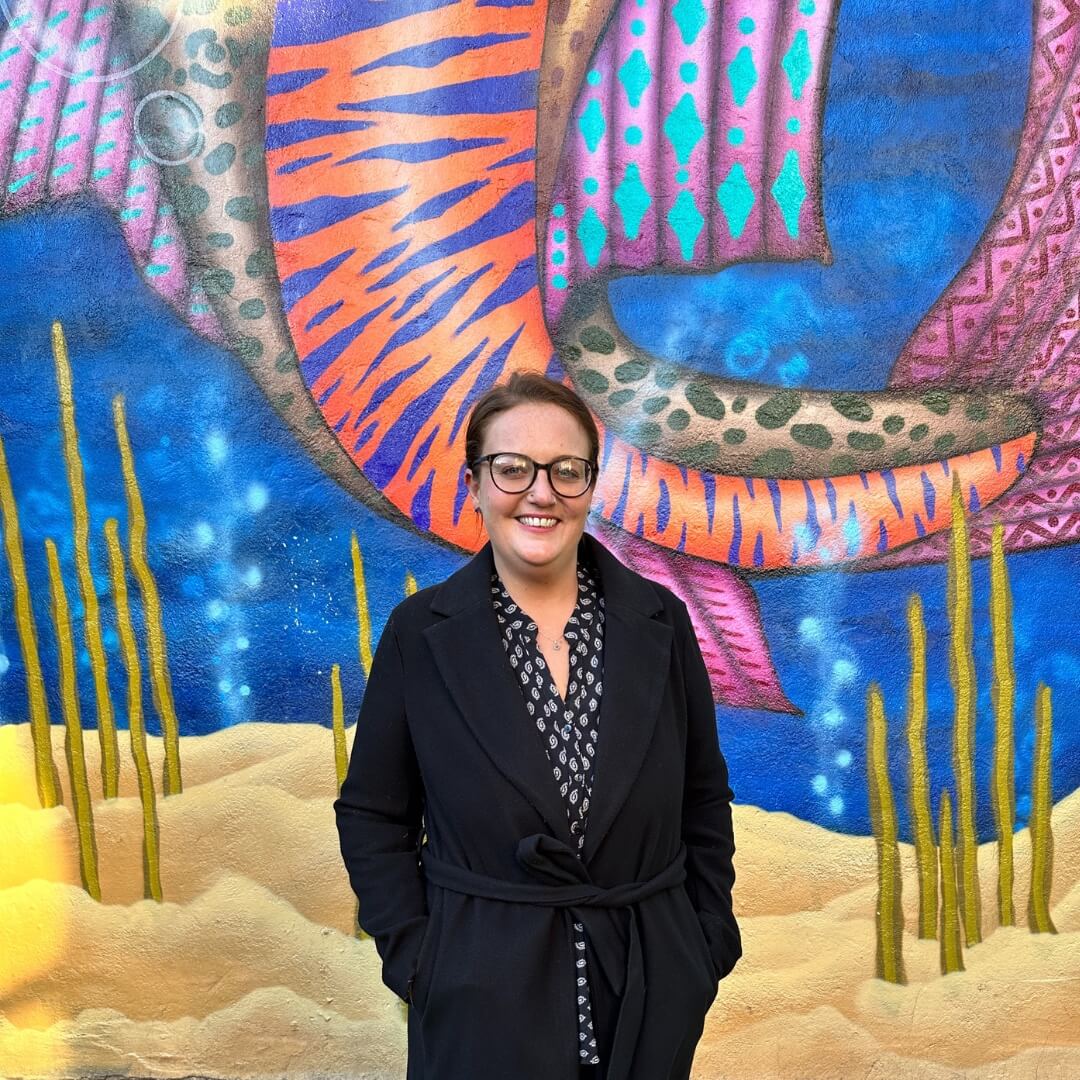 Amy standing in front of a painted mural