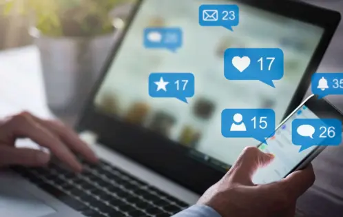 Man using social media on a laptop and phone with super imposed messaging bubbles and notifications.
