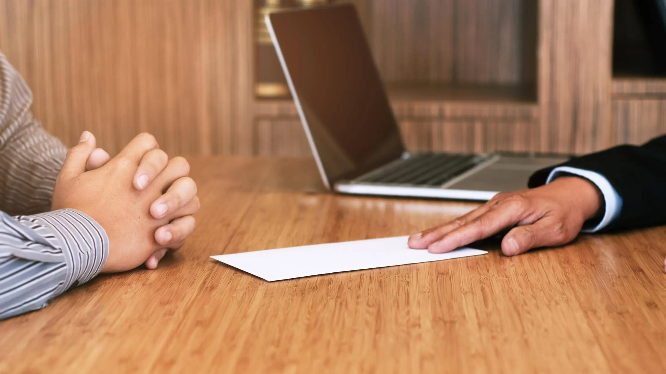Man sliding an envelope containing a resignation letter to his employer across a desk.